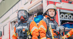 Zwei Männer in Feuerwehruniform stehen vor einem Feuerwehrauto. Foto: IW Medien / Joshua Murat