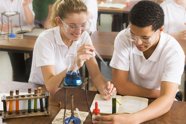 Neugier zahlt sich aus: Schülerin und Schüler beim Chemie-Experiment im Klassenraum. Foto: Storyblocks